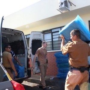 Policiais descarregam cigarro que estava em van com adesivos falsos da Secretaria de Saúde do Estado do Paraná; veículo foi apreendido em Cambé (Foto: Portal Cambé)
