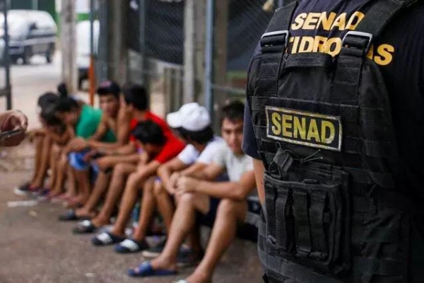 Agente da Senad vigia jovens presos por tráfico de drogas no Paraguai (Foto: Divulgação)